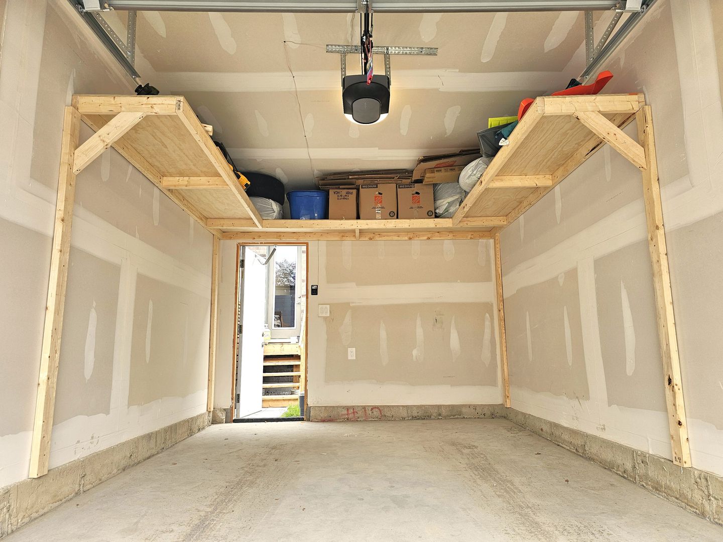 Wrap-around overhead wood garage shelving loaded with bins and boxes in a single garage in Toronto — built on-site by Toronto Garage Storage.