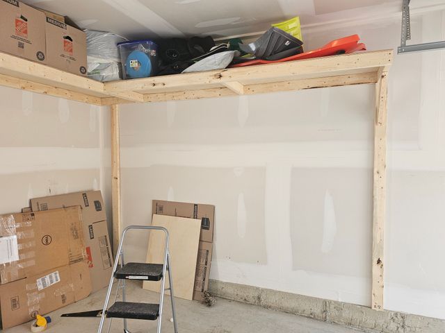 Overhead wood garage shelving loaded with sleds, bins and boxes in a single garage in Toronto — built on-site by Toronto Garage Storage.